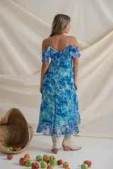 Vestido midi de gasa estampada en tonos azules, con escote cruzado, breteles finos y volados desde los breteles hasta el ruedo. Más corto adelante.