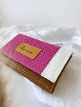 Billetera de cuero con estampado reptil en color marrón y fucsia con detalles en blanco. Tiene un sistema de cierre con broche y monedero externo.