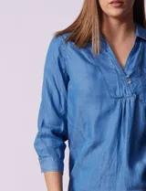 Blusa celeste de lyocell con cuello con solapa, escote en V y cierre con botones. Tiene un bolsillo en el pecho, mangas 3/4 con puño y botón.