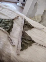 Conjunto de lencería de encaje verde musgo con detalles en beige, compuesto por un corpiño triangular sin aro y una tanga con tiras ajustables.