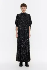 Vestido largo de lentejuelas negro, con corte recto y escote subido, manga larga con volumen y detalles en los puños.