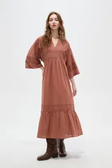 Vestido largo color marrón, con escote en V, mangas 3/4 y detalles de broderie en el pecho, mangas y falda. La falda tiene un volado en el ruedo.