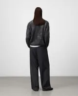 Sweater de punto jacquard cardado en color gris oscuro con diseño de manchas abstractas. Presenta cuello redondo, manga larga y una textura suave y ligera.