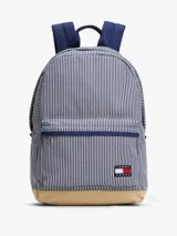 Mochila Tommy Jeans Essential con diseño a rayas verticales azules y blancas, base color beige, asa superior y correas acolchadas ajustables. Cuenta con compartimento principal con cierre de cremallera, bolsillo interior de malla y bolsillo exterior con cremallera.