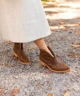 Botines de cuero vacuno color blanco con diseño bordado, taco de madera foliado en cuero de 5cm, cierre del lado interior y horma de punta fina.