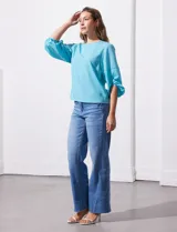 Blusa de gasa color blanco con estampado de hojas verdes, de mangas 3/4 abullonadas con puños elásticos.