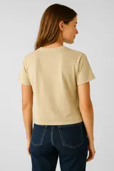 Remera color beige de algodón con estampado de dos perros y una palmera enmarcada en un arco con detalles florales.