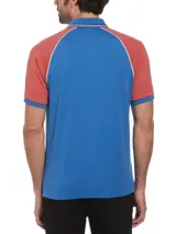 Chomba de hombre con mangas cortas raglán, color azul con mangas color ladrillo y detalles en blanco. Confeccionada en tejido interlock de algodón orgánico y logo bordado en el pecho.