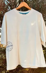 Remera color crema de corte amplio con cuello redondo y mangas cortas. Estampa circular en el frente con diseño geométrico y la palabra "Vancouver" en color azul.