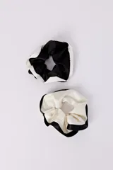 Pack de dos scrunchies, uno negro con borde blanco y otro blanco con borde negro.