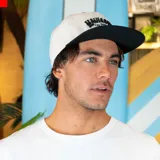 Gorro snapback blanco con visera plana negra y logo de Maui and Sons bordado en negro en el frente.