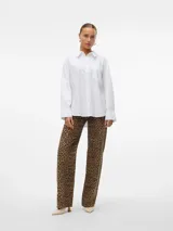 Camisa blanca oversize con hombros caídos y bolsillo frontal.