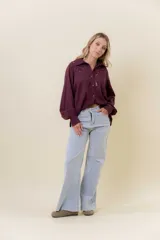 Pantalón de jean estilo wide leg, color celeste claro, con tiro medio, cinco bolsillos y cierre frontal con botón y cremallera.