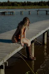 Vestido corto marrón de gamuza sintética, sin mangas, con escote en V y detalle de flecos en el ruedo. Presenta apliques bordados en el frente y laterales.