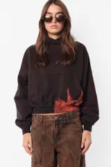 Buzo de frisa negro con proceso artesanal de teñido rosa en mangas y ruedo, tipo hoodie, silueta boxy, puños y cintura de rib, capucha forrada en su interior y bolsillo canguro.