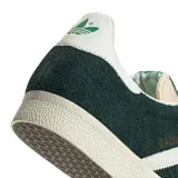 Championes Adidas Gazelle color verde oscuro con las tres tiras laterales blancas y suela color crema.