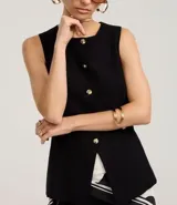 Chaleco negro de sastrería con cuello redondo, cierre frontal con botones dorados y bajo estructurado con recortes anatómicos.