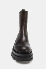 Botín de estilo urbano con efecto desgastado, confeccionado con suela de plataforma dentada y puntera redonda. Cuenta con un diseño tipo pull-on y tirador trasero para facilitar el calce.