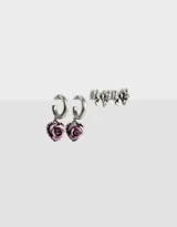 Set de dos pares de aros plateados: un par de argollas con dije de rosa color lila y un par de aros tipo botón con forma de moño.