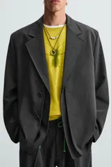 Blazer negro de corte relajado con cuello de solapa de muesca desmontable, manga larga, bolsillos frontales ocultos y cierre frontal con botones.