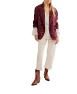 Blazer cruzado de corte oversize, con solapas amplias y hombros estructurados. Presenta un estampado tartán en tonos burdeos, morado y amarillo.