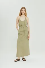 Vestido largo color verde oliva, con escote halter y lazo ajustable en la cintura. Presenta bolsillos laterales y corte recto.