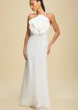 Vestido largo blanco con escote halter y detalle de flor grande en el pecho.