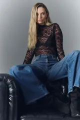 Pantalón jean oxford de tiro alto, confeccionado en denim azul con desgaste localizado y bigotes.