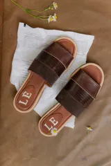 Sandalias planas de cuero marrón con tira ancha sobre el empeine. La plantilla es de cuero con la inscripción "LE".