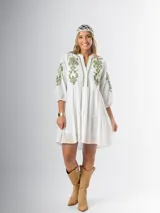 Vestido corto blanco de algodón italiano con bordado azul, mangas tres cuartos y botones frontales.