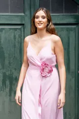 Vestido largo color lila con escote en V cruzado y detalle de flor grande en la cintura.