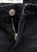 Pantalón de jean negro de corte wide leg, tiro alto y largo hasta el tobillo. Presenta trabillas, cinco bolsillos y bajo deshilachado. Cierre frontal con cremallera y botón.
