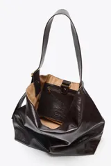 Bolso maxi shopper color marrón oscuro, con asa ancha ajustable con hebilla. Incluye bolsillo interno con cierre de cremallera metálica y cierre imantado.