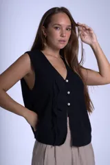 Chaleco tejido color crudo con cuello en V y cierre frontal con tres botones de perlas y lazos decorativos.
