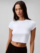 Remera corta blanca de algodón y elastano, con cuello redondo, mangas cortas y logo de Calvin Klein en el pecho.