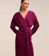 Vestido midi de satén color fucsia, con escote cruzado en V, mangas largas evasé, pliegues delanteros y cierre trasero con cremallera y cordones.