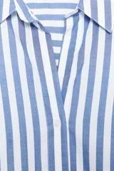 Camisa celeste y blanca a rayas verticales, de corte recto, con cuello solapa y mangas largas con puños abotonados.