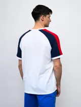 Remera de algodón azul con mangas ranglan azul marino y detalles en blanco en cuello y puños. Incluye logo de Umbro y escudo del Club Nacional de Football en el frente.