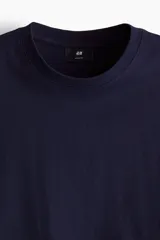 Remera azul marino de punto de algodón pesado, con cuello redondo ribeteado, hombros caídos y bajo recto. Corte holgado.