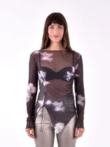 Body de tul negro con estampado de flores blancas y celestes, corte irregular en la parte inferior y mangas largas.