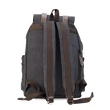 Mochila de tela canvas color verde oliva con tapa y detalles en símil cuero marrón. Cierre superior marinero, bolsillos internos, externos frontal, laterales y trasero con cierre. Asas rígidas, correas ajustables y espacio para laptop de 15".
