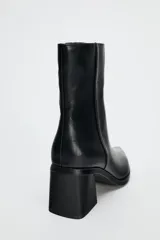 Botín de cuero negro con punta fina, cierre lateral con cremallera y tacón ancho de 6 cm.