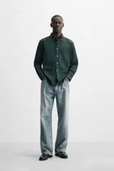 Camisa azul marino de corte regular fit, confeccionada en tejido de algodón Oxford. Tiene cuello abotonado, manga larga con puños abotonados, bolsillo de parche en el pecho y cierre frontal con botones.