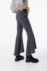 Pantalón de jean gris elastizado con volados en la parte baja de la pierna, ruedo irregular y terminación desflecada.