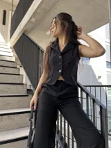 Conjunto negro de chaleco sastrero con botones y pantalón palazzo de tiro alto. El chaleco es entallado y el pantalón es de corte amplio.