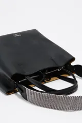 Bolso de hombro estructurado de piel vacuna negra, con doble asa de mano y asa regulable de tejido a rayas. Presenta cierre de cordón, logo metálico frontal y bolsillo interior con cierre de cremallera.