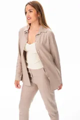 Conjunto color beige compuesto por camisa de manga larga con botones, musculosa blanca de breteles finos y pantalón largo de vestir.