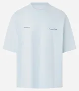 Remera de algodón celeste claro, corte oversized, con cuello redondo y manga corta. Presenta un pequeño texto bordado en azul oscuro en el pecho a cada lado.