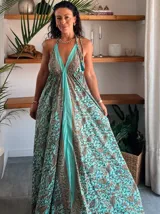 Vestido largo tipo solera, color turquesa con estampado paisley en tonos marrones y dorados. Diseño con escote halter anudado al cuello y abertura frontal central en color liso.