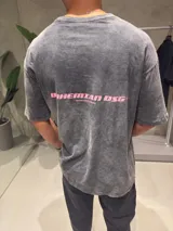 Remera oversize de algodón 100% color gris oscuro con efecto lavado, y estampado trasero en color rosa que dice "BHEMIAN DSG" y "CERTIFIED AUTHENTIC STREETWEAR".